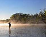 Mists rise off the water as a fisherman begins his day.