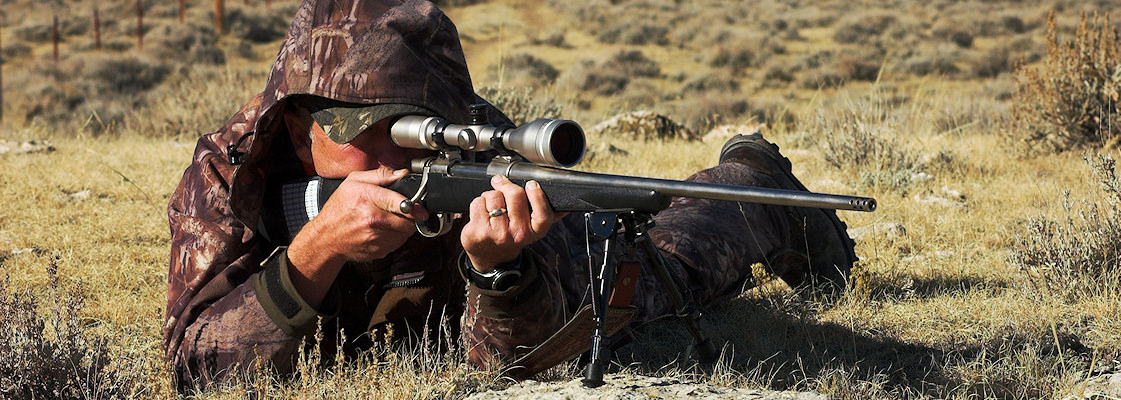 A hunter looks through his scope and prepares to fire his rifle.