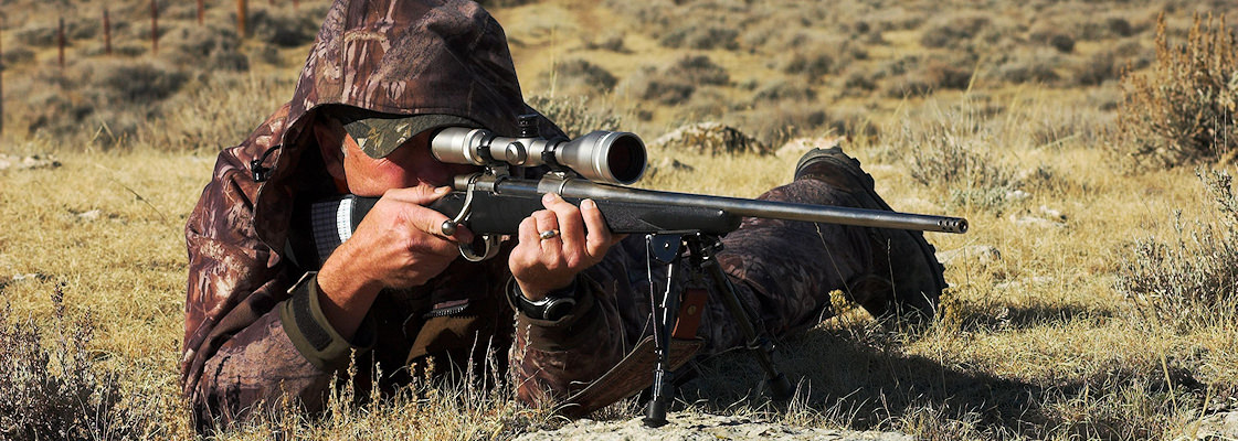 A hunter looks through his scope and prepares to fire his rifle.