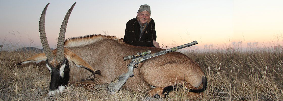 A hunter sits behind his roan antelope trophy.