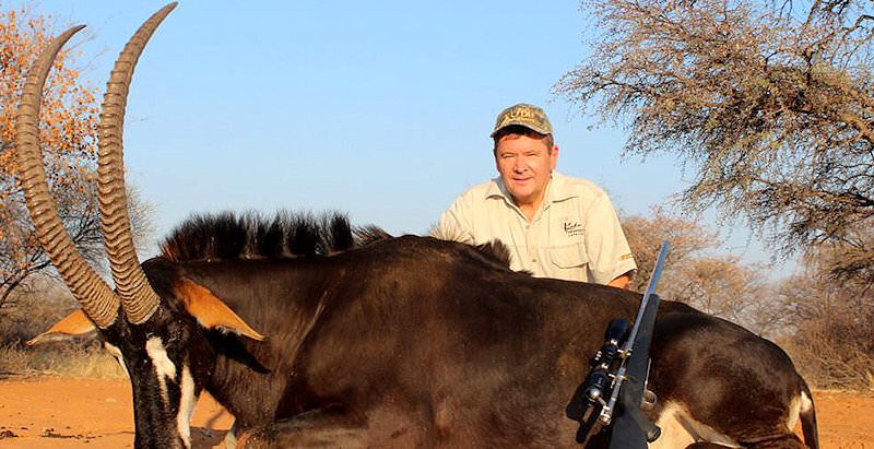 A hunter sits behind his impressive Sable antelope trophy.