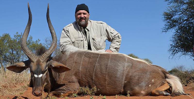 A hunter smiles alongside his nyala trophy.