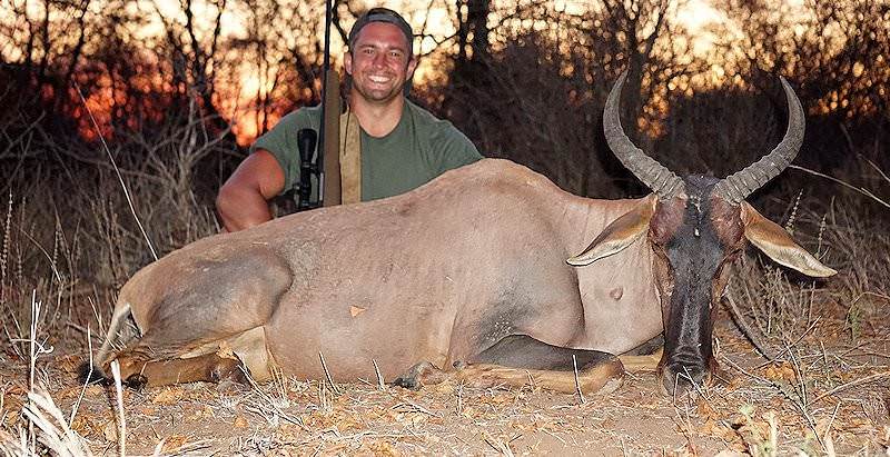 A hunter smiles with his tsessebe trophy at sunset.