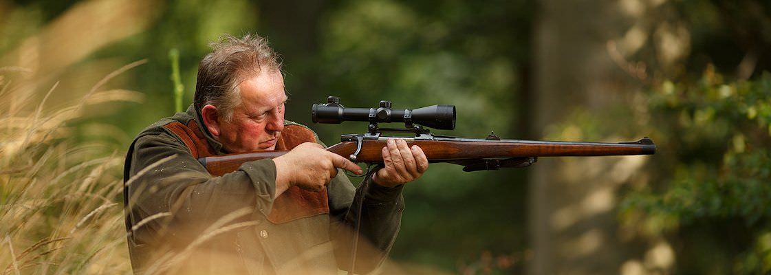 A hunter prepares to take a shot with his rifle.